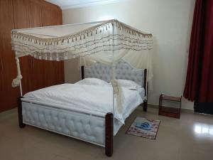 um quarto com uma cama de dossel com lençóis brancos em Amigo apartments em Kisumu
