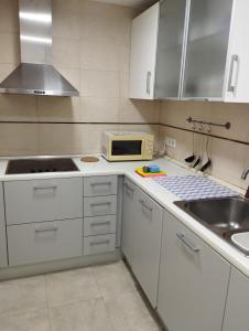 cocina con armarios blancos, fregadero y microondas en Apartamento en Barcelona en Barcelona