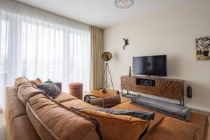 a living room with a brown couch and a flat screen tv at Park-Apartment Scharmützelsee Wohnung 12 in Wendisch Rietz