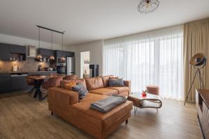 a living room with a brown couch and a kitchen at Park-Apartment Scharmützelsee Wohnung 12 in Wendisch Rietz