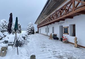 a snow covered building with tables and umbrellas at Penzion Golf Luby 