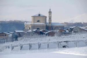a large building with a clock tower in the snow at 4 TEA 4 HOUSE in Romano Canavese