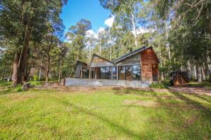 a log cabin in the woods with a yard at Black Mamba House in Harrietville