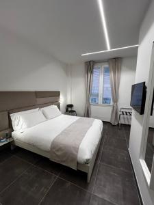 una camera da letto con un grande letto bianco e una televisione di Joyfül Accomodation a Finale Ligure