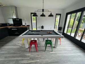a ping pong table in a room with colorful stools at Jolie Villa avec SPA et Balnéothérapie in Martignas-sur-Jalle