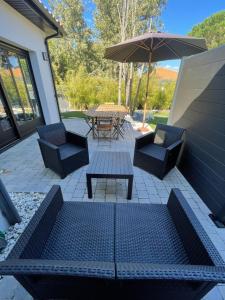 eine Terrasse mit einem Tisch, Stühlen und einem Sonnenschirm in der Unterkunft Jolie Villa avec SPA et Balnéothérapie in Martignas-sur-Jalle