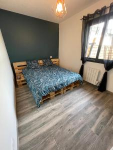Schlafzimmer mit einem Bett mit blauer Decke in der Unterkunft Jolie Villa avec SPA et Balnéothérapie in Martignas-sur-Jalle