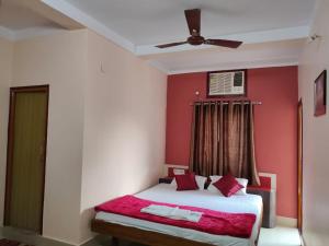 een slaapkamer met een bed met rode muren en een plafond bij Hotel Vaishnavi near Baba Dham Temple in Deoghar