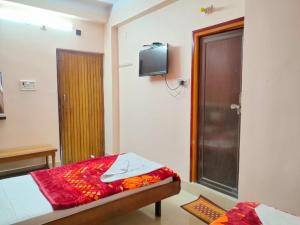 een slaapkamer met een bed en een tv aan de muur bij Hotel Vaishnavi near Baba Dham Temple in Deoghar