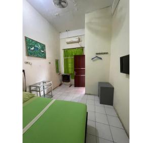 a room with a green bed and a television at OYO 93341 Ananda Homestay Syariah in Pekanbaru