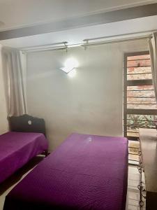 a bedroom with purple beds and a window at Manors' Holiday Home in Durban