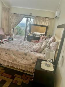 a bedroom with a large bed with a table and a window at Manors' Holiday Home in Durban