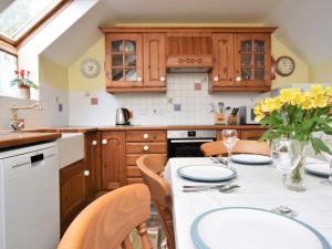 una cocina con armarios de madera y una mesa con flores amarillas. en 3 bed property in Bideford HONEY en Frithelstock