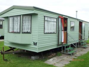 une petite maison verte exposée dans une cour dans l'établissement Caravan 309 Bryn Y Mor Beach Side Park, à Tywyn