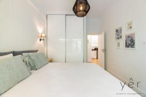 een witte slaapkamer met een groot bed en een hanglamp bij Trendy Living in Koukaki! "Hotspot!" Nighttime noise possible in Athene