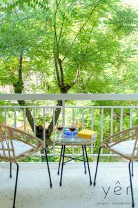een tafel en twee stoelen op een veranda met een boom bij Trendy Living in Koukaki! "Hotspot!" Nighttime noise possible in Athene