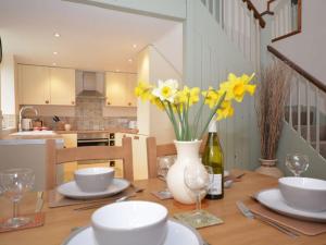 a dining room table with yellow flowers in a white vase at 2 bed in Watchet OLDSO in Wiveliscombe