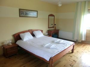 a bedroom with a bed with white sheets and a mirror at Liedags Guesthouse in Jūrkalne