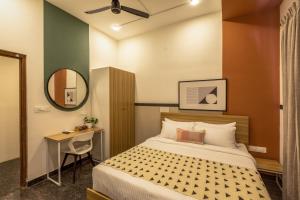 a bedroom with a bed and a desk and a mirror at Olive Domlur - by Embassy Group in Bangalore
