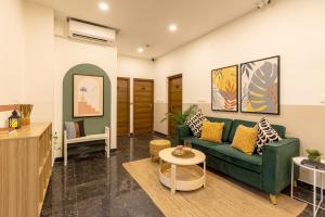 a living room with a green couch and a table at Olive Domlur - by Embassy Group in Bangalore