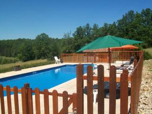 a swimming pool with a green umbrella and chairs at Le Bos de Montassot in Savignac-les-Églises