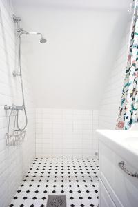 uma casa de banho com chuveiro e piso em azulejo preto e branco em Eklinds Rum och Trädgård em Gotemburgo