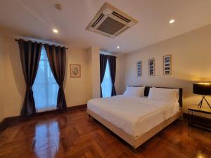 Chez Moi Bangkok Private Executive Residence Sukhumvit 26 في Klong Toi: غرفة نوم بسرير ابيض كبير وارضيات خشبية