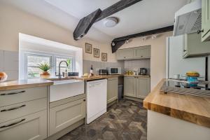 a large kitchen with white cabinets and a window at Ivy Cottage in Buckland in the Moor