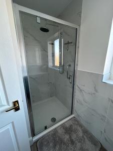 a shower with a glass door in a bathroom at Magnolia House in Royston