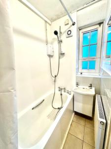 baño blanco con ducha y lavamanos en Flat in Vauxhall Explore London, en Londres