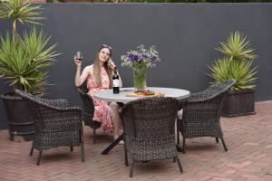 a woman sitting at a table with a glass of wine at Arvella Guesthouse in Bloemfontein