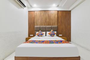 a bedroom with a large bed with a wooden headboard at FabHotel Maan Palace in Naroda