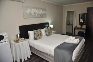 a bedroom with a large white bed with a table at Arvella Guesthouse in Bloemfontein +30 photos