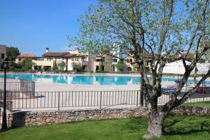 a swimming pool with a fence and a tree at Lugana Resort & Sporting Club - Sermana Village in Peschiera del Garda