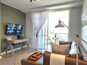 ein Wohnzimmer mit einem Sofa und einem Tisch mit einem TV in der Unterkunft Brizzy's Balcony A Well-located Luxe Retreat in South End