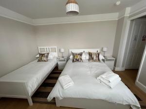 a bedroom with two beds with white sheets and pillows at Magnolia House in Royston