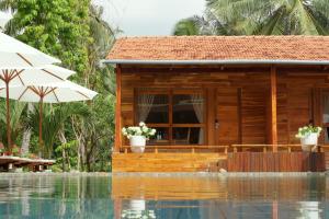 a house next to a swimming pool with an umbrella at Bauhinia Resort & Spa Phu Quoc in Phú Quốc