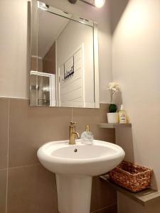 y baño con lavabo blanco y espejo. en Brizzy's Balcony A Well-located Luxe Retreat, en South End
