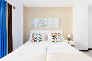 a bedroom with a large white bed with pillows at COMODORO- RAVEL in Los Cristianos
