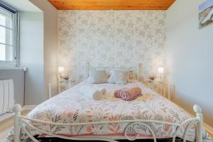 een slaapkamer met een wit bed en een sprei met bloemen bij Bord de Rance - Le Gîte de Louise in Pleudihen-sur-Rance