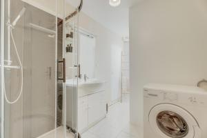 een witte badkamer met een wasmachine en een wastafel bij Bord de Rance - Le Gîte de Louise in Pleudihen-sur-Rance
