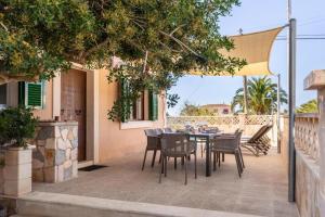 a patio with a table and chairs under an umbrella at Villa Sa Llimonera by Slow Villas in Es Llombards