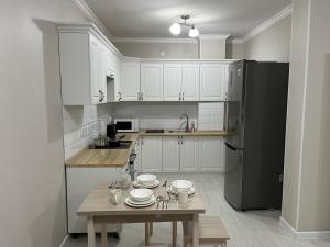 La cuisine est équipée de placards blancs et d'un réfrigérateur noir. dans l'établissement Времена года лето, à Taldykolʼ