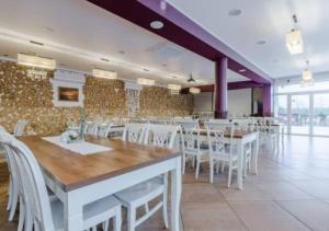 a dining room with white tables and white chairs at Pensjonat nad Jeziorem in Powidz