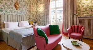 ein Schlafzimmer mit einem Bett, einem Stuhl und einem Sofa in der Unterkunft Hotel Kung Carl, WorldHotels Crafted in Stockholm