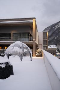 una sombrilla cubierta de nieve frente a un edificio en DOLOMITI EXCLUSIVE YOUR MOUNTAIN SUITE en Pozza di Fassa