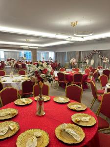 a banquet room with tables and chairs with red tablecloths at Hôtel Ivotel Abidjan in Abidjan