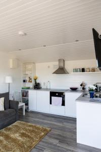 a kitchen with white cabinets and a living room at doolinyoga luxury accommodation in Doolin