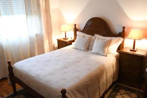 a bedroom with a bed with two lamps and a window at Casa Raposo in Miranda do Corvo