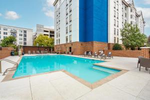 Hampton Inn & Suites Nashville-Vanderbilt-Elliston Place في ناشفيل: مسبح وكراسي ومبنى في الخلف